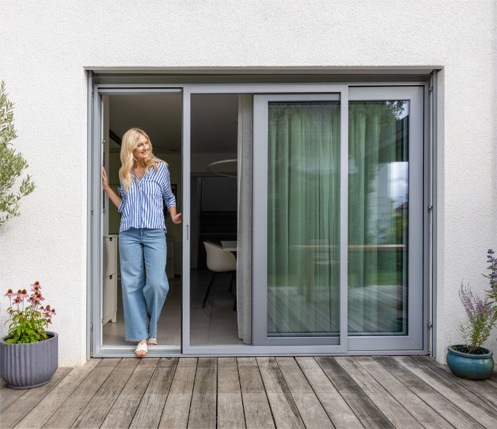 Insektenschutz‑Schiebetür mit feinem Gewebe vor einer großen Glas-Schiebetür, Rahmen wird seitlich in der Führung bewegt.