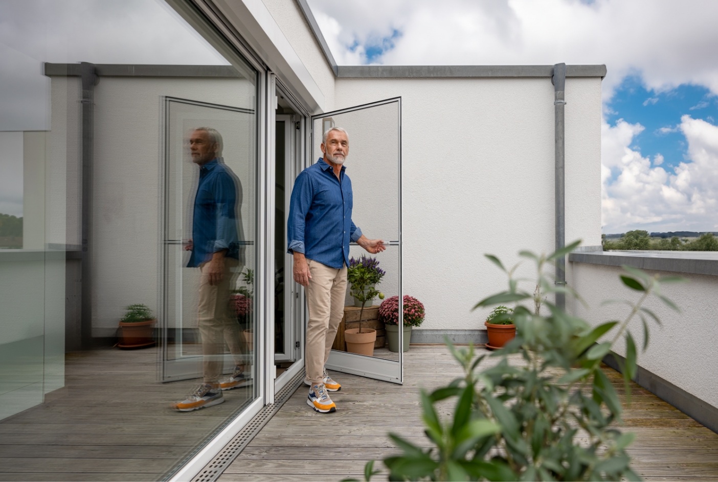 Mann geht durch Neher Insektenschutz Drehtür auf den Balkon.